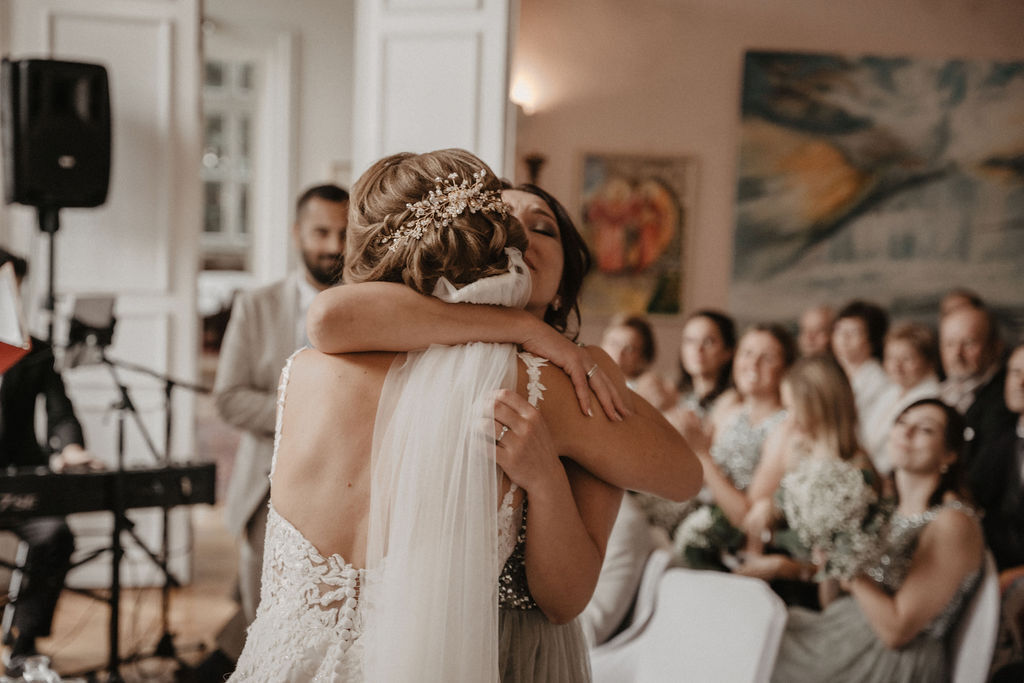 Eine Braut wird von einer Freundin herzlich umarmt