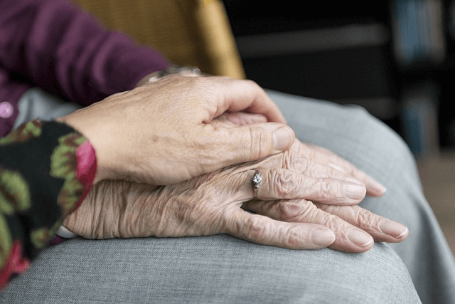 Hilfe bei Trauerbewältigung - Jemand hält die Hand einer alten Dame